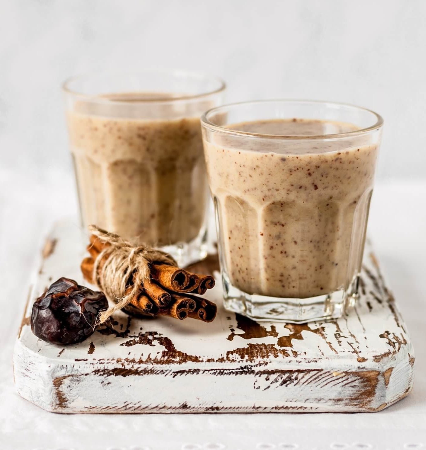 Two glasses of almond smoothie sitting on board