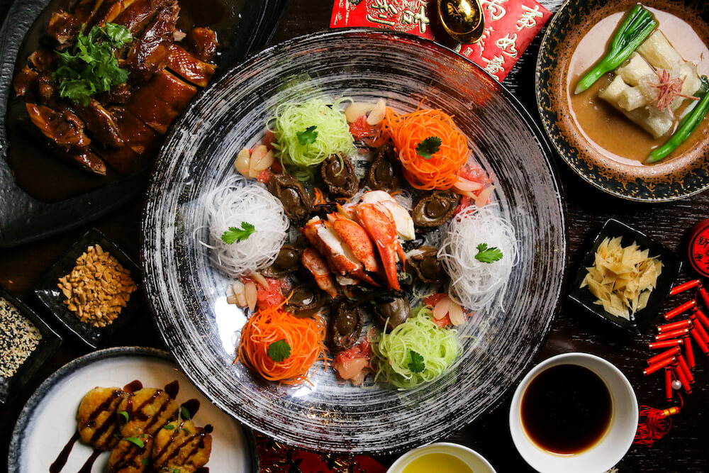 A yusheng salad from above with other dishes surrounding it.