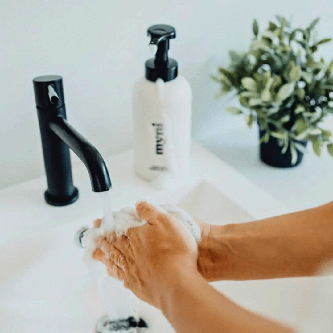 A closeup of someone washing their hands at a sink.