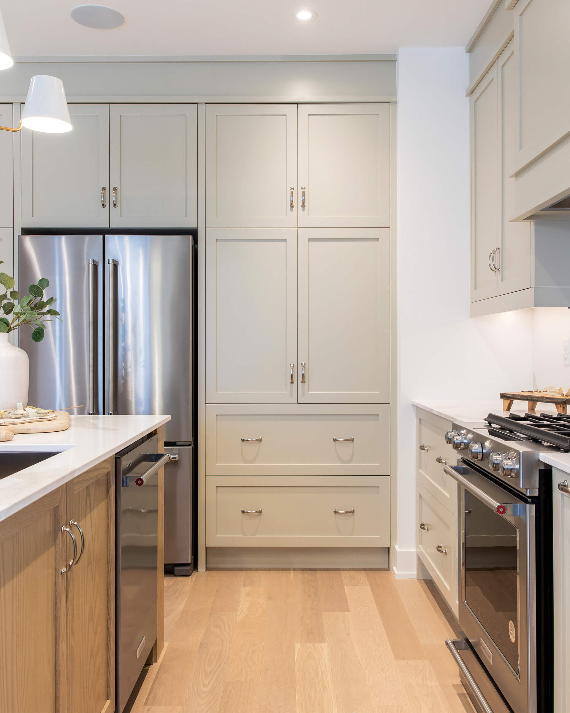 A view of a kitchen with light green cabinetry and stainless steel appliances.