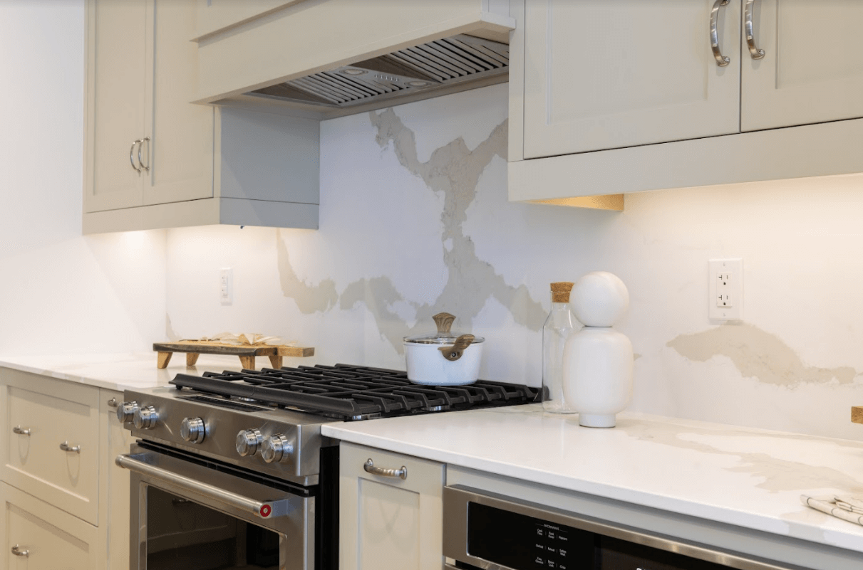 A closeup shot of a stove with marbled backsplash.