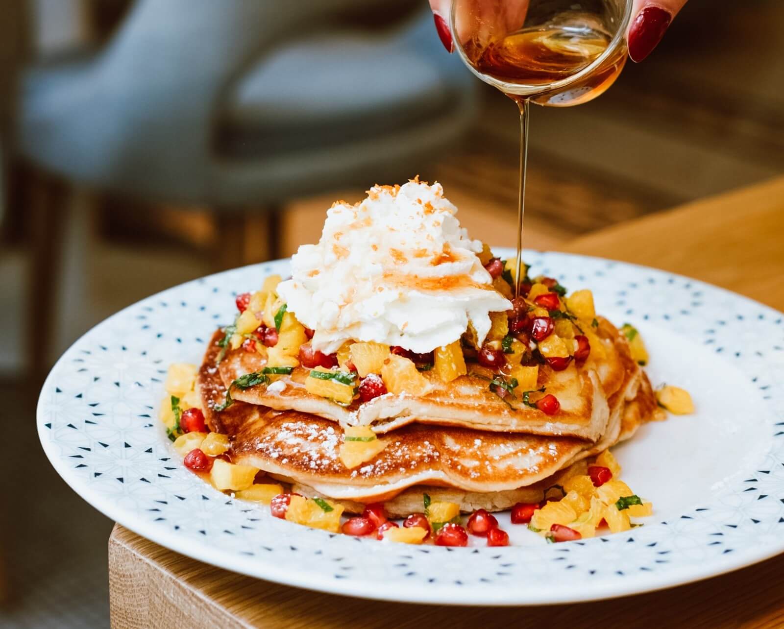 Syrup being poured over pancakes
