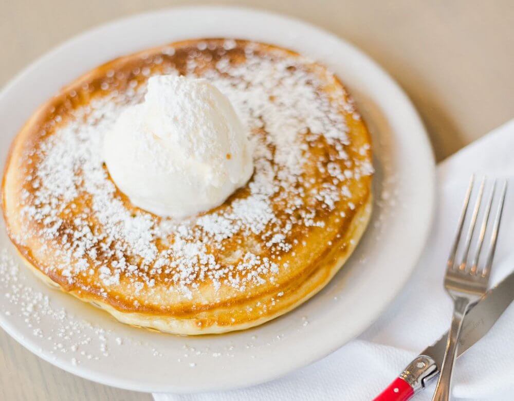 Pancakes with icing sugar and a scoop of ice cream on top