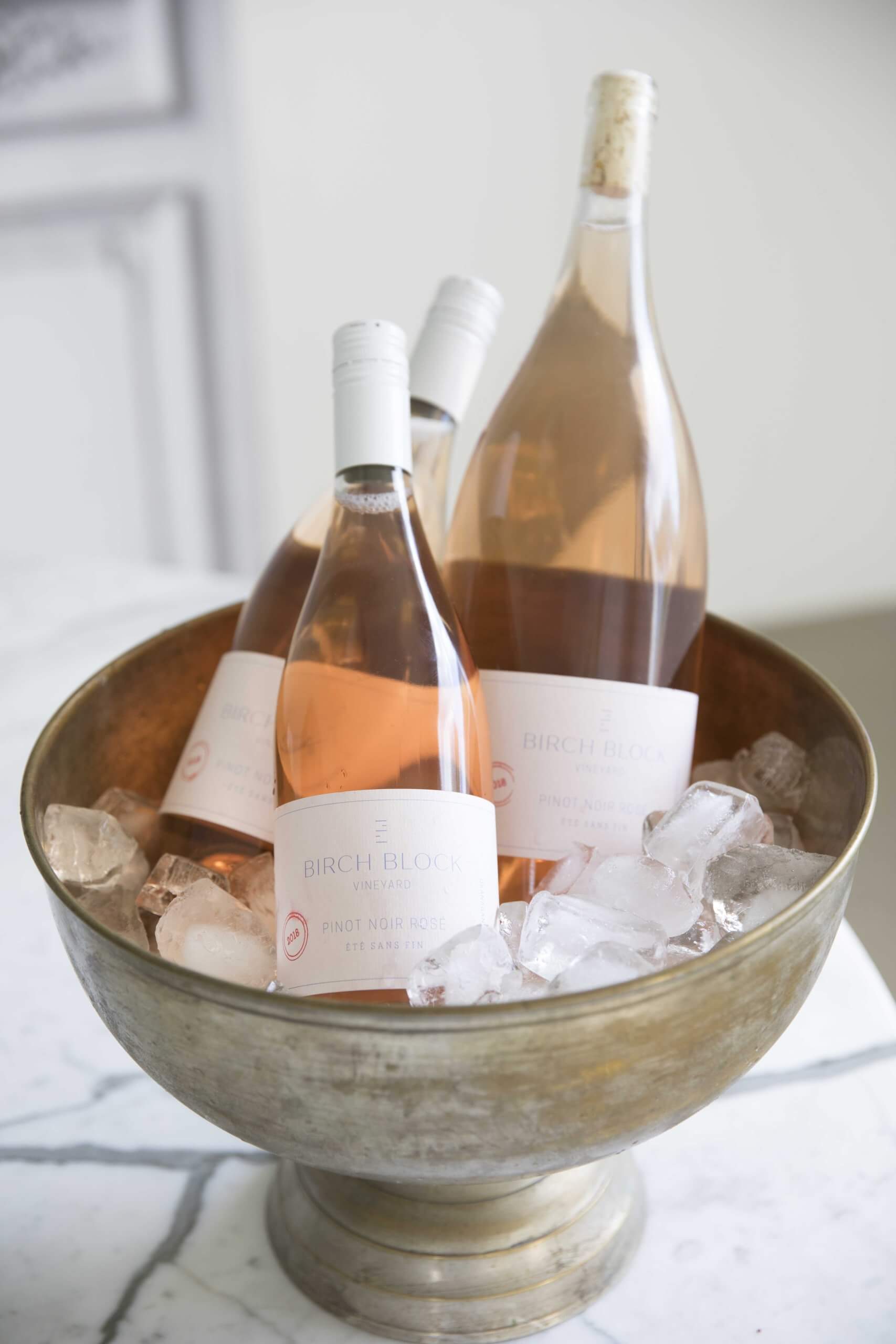 Three bottles of rosé wine in a round metal ice bucket