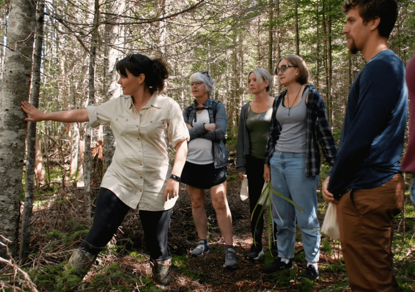 A woman speaking to a group of people in the woods