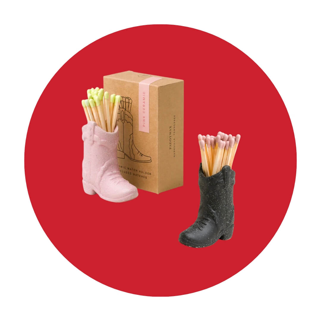 A small pink and black cowboy boot with coloured-tipped matches in them and a cardboard box on a red circle graphic