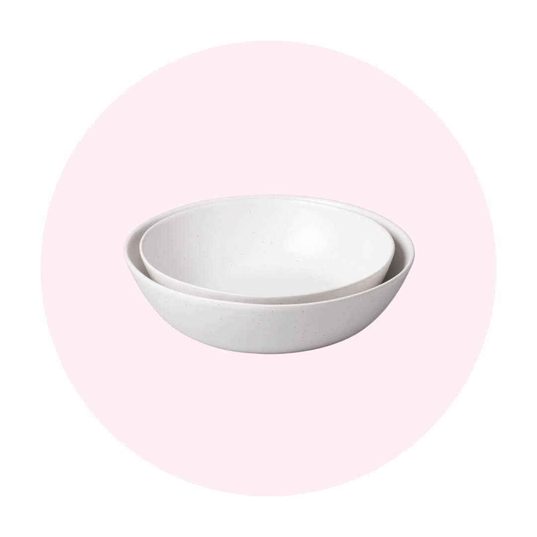 Three white bowls stacked on a light pink circle graphic 