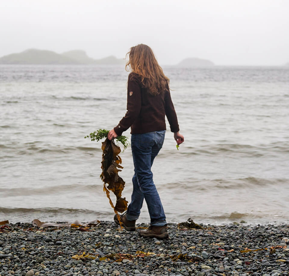 A woman walks along a stony beach