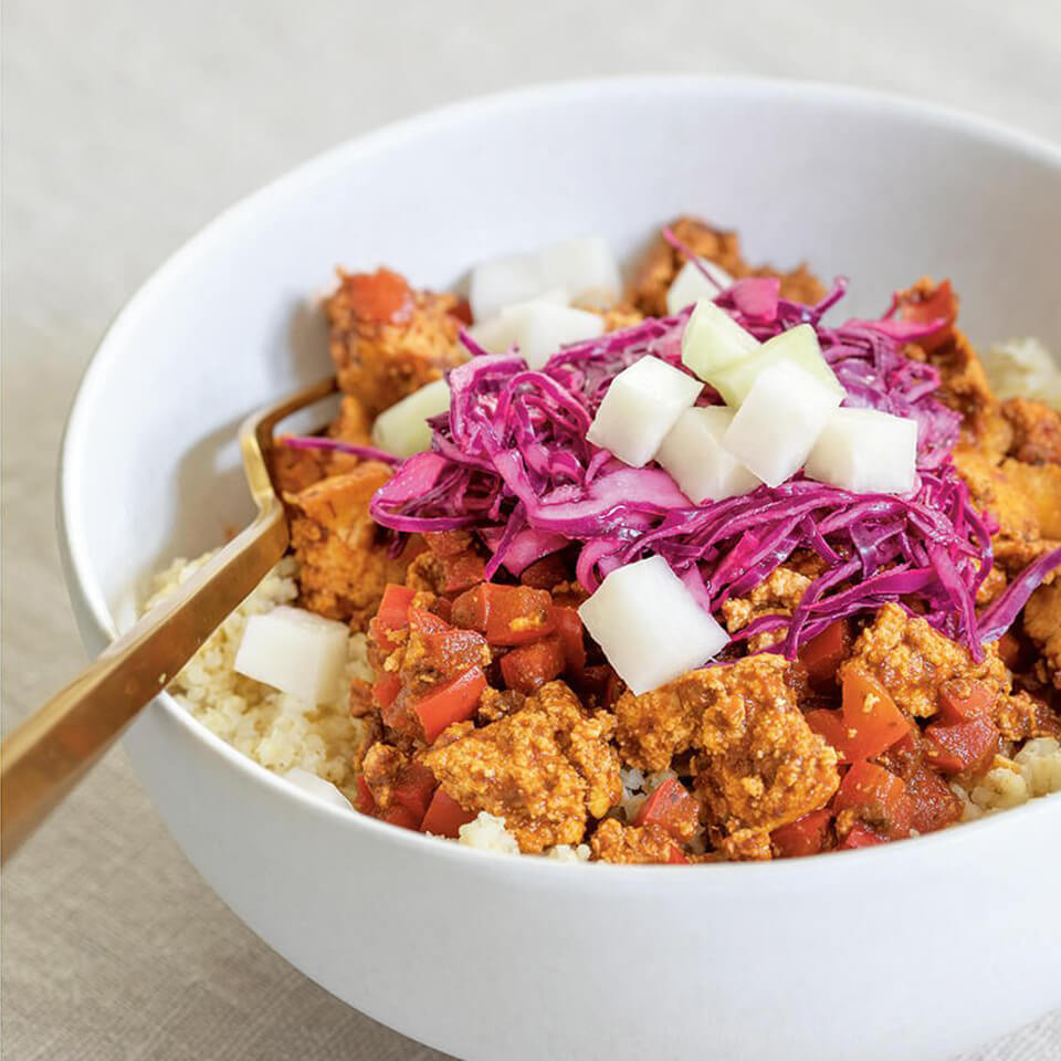 A white bowl with tofu and sofrito sauce