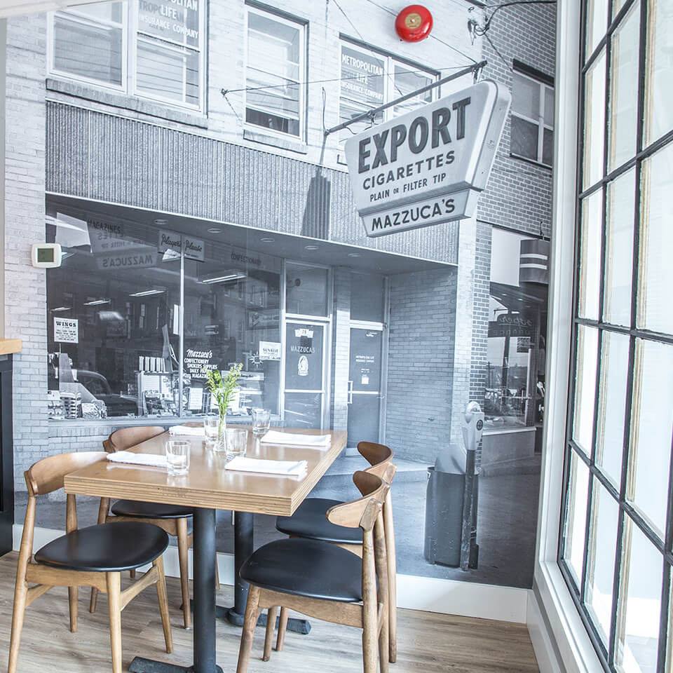 A dining table with a large black-and-white photograph of a storefront on the wall behind it