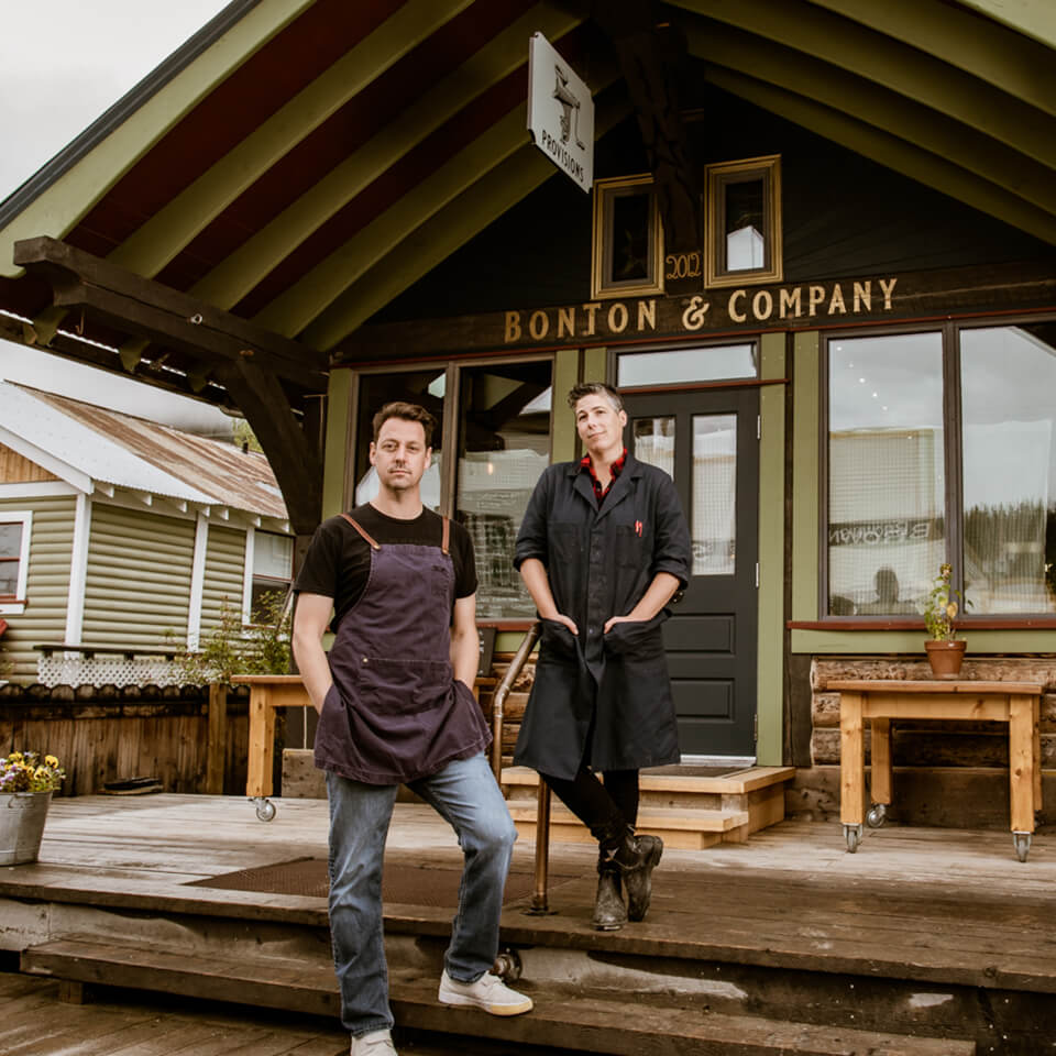 Two people standing on the steps of a wooden storefront