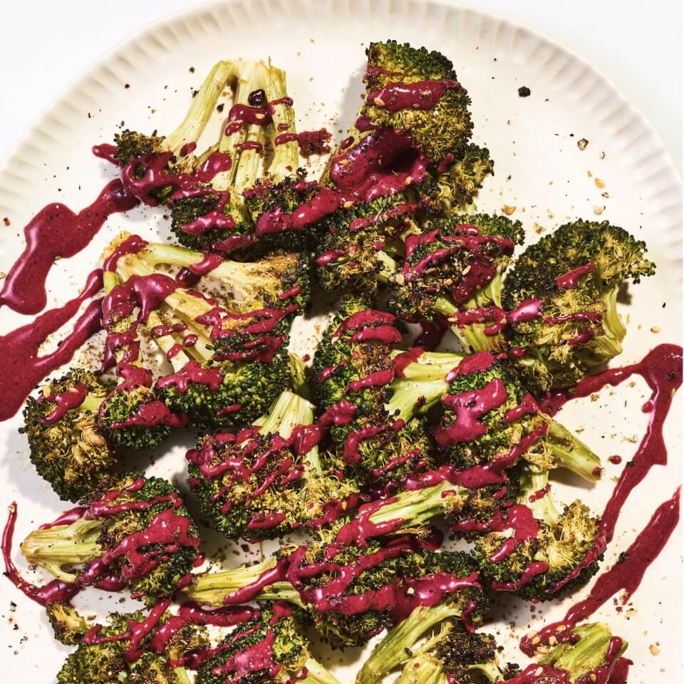 A dish of roasted broccoli drizzled with beet tahini