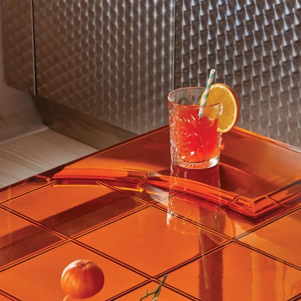An orange drink on top of a bright orange tile table