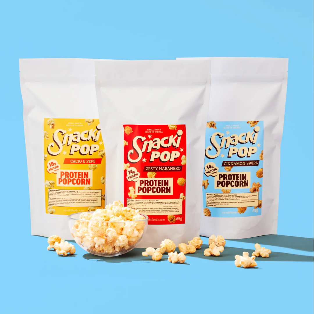 A small bowl of popcorn in front of three white bags of popcorn.