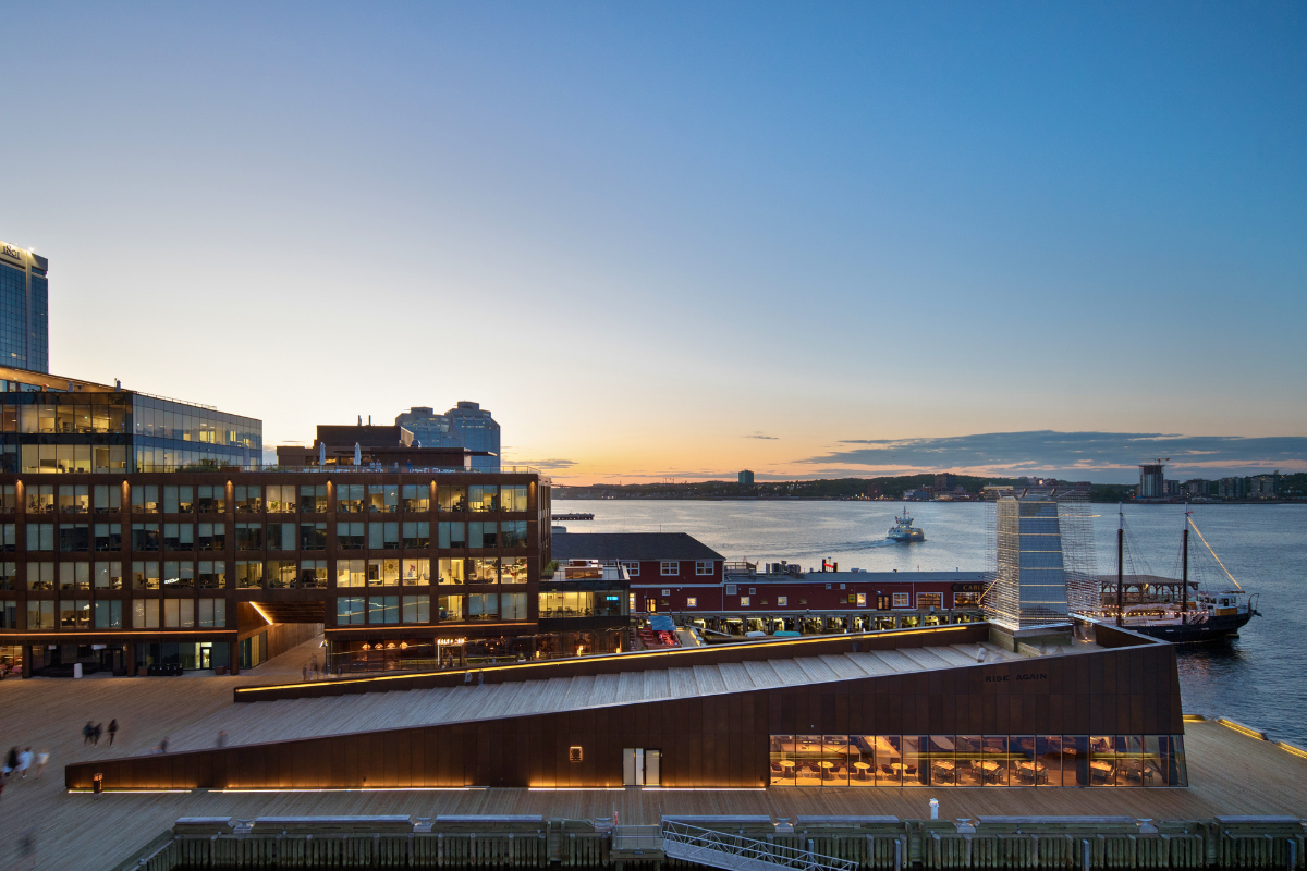 Mystic restaurant inside the wedge-shaped Rise Again structure on the Halifax waterfront at sunset.
