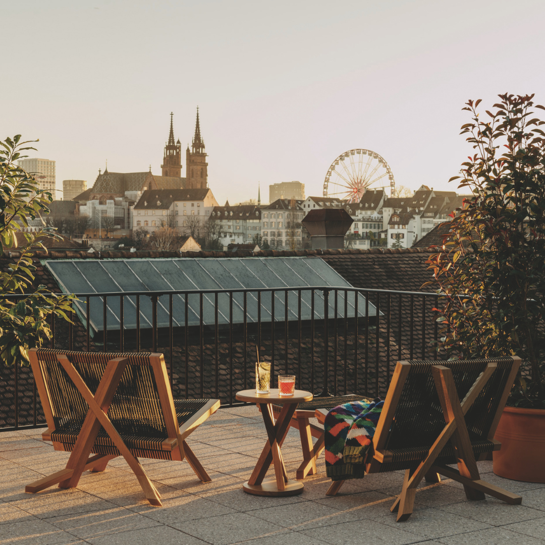 Two lounge chairs on a terrace overlooking a view of Basel.