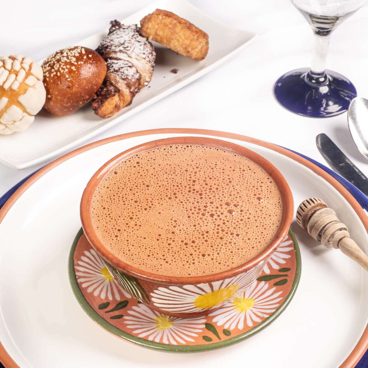 A mug of drinking chocolate in a patterned cup with desserts in the background.