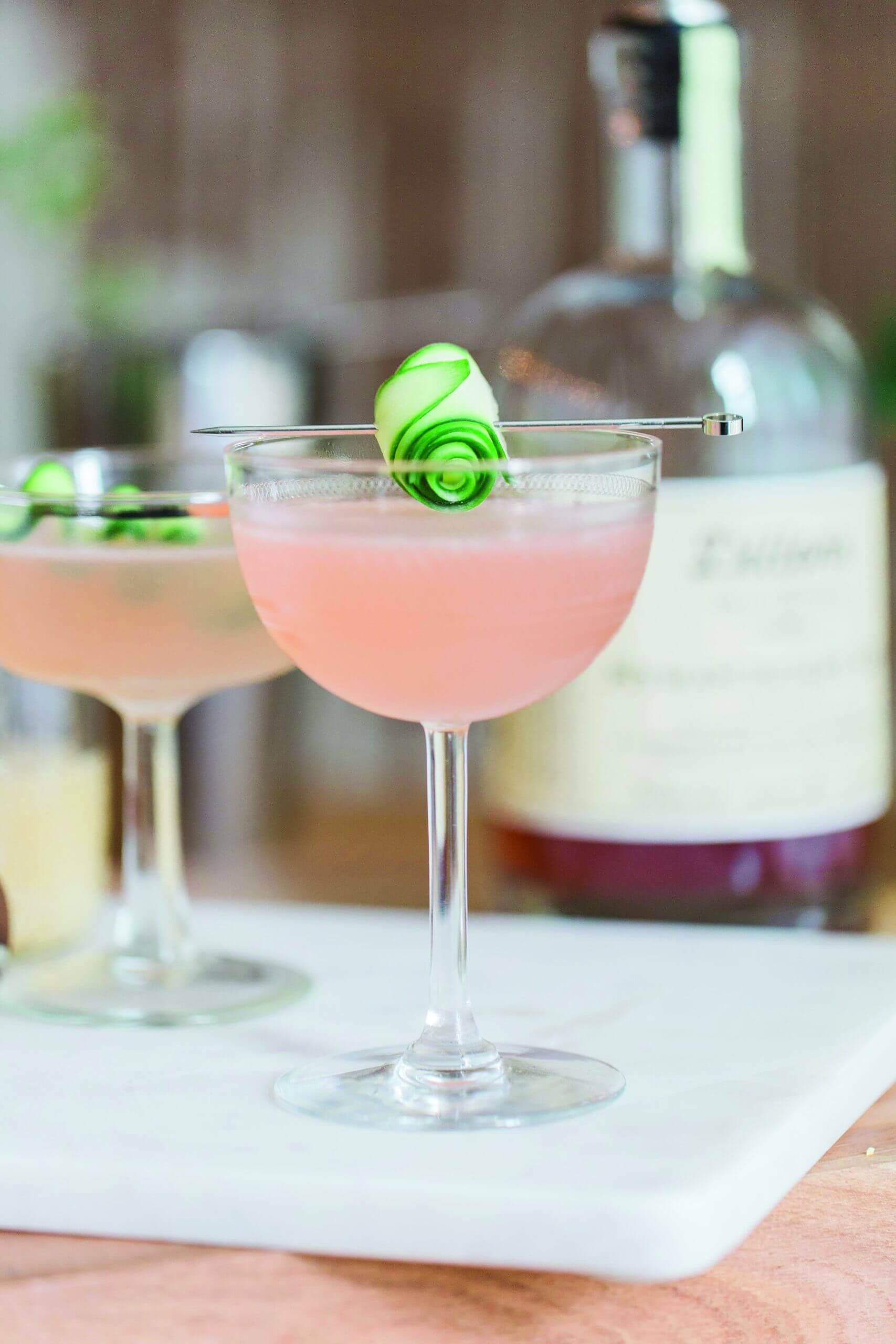 Gorgeous pink cocktail with a rolled-up cucumber garnish all made with Canadian company Dillon's gin