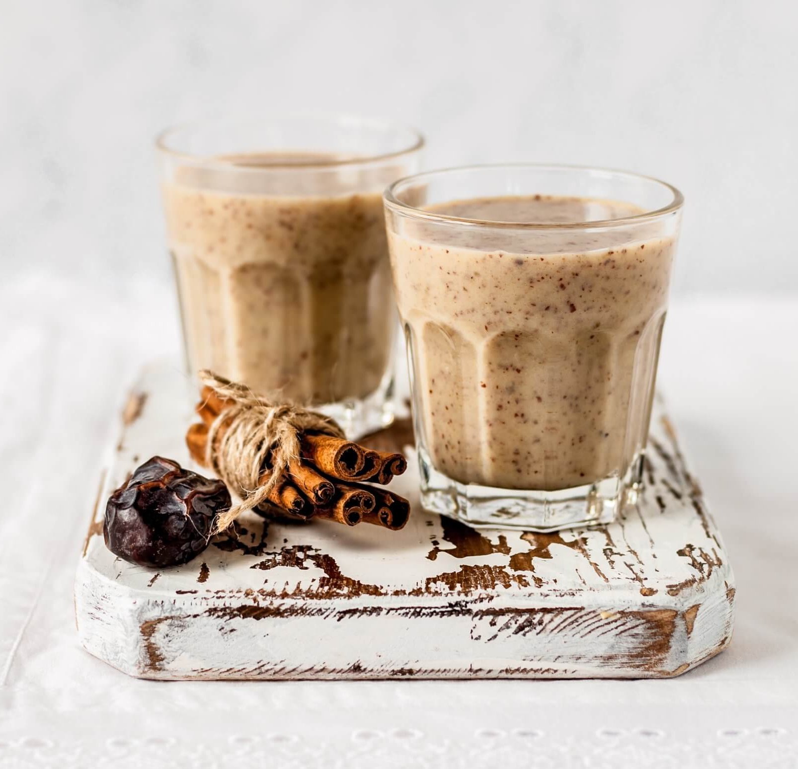 Two glasses of almond smoothie sitting on board
