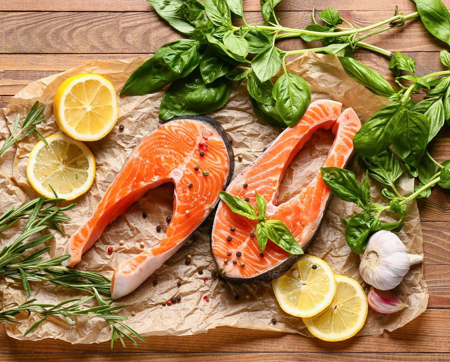 raw salmon, slices of lemon and fresh basil on cutting board