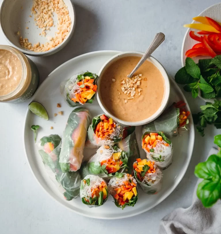 A plate of vegetable spring rolls with peanut sauce on a plate.
