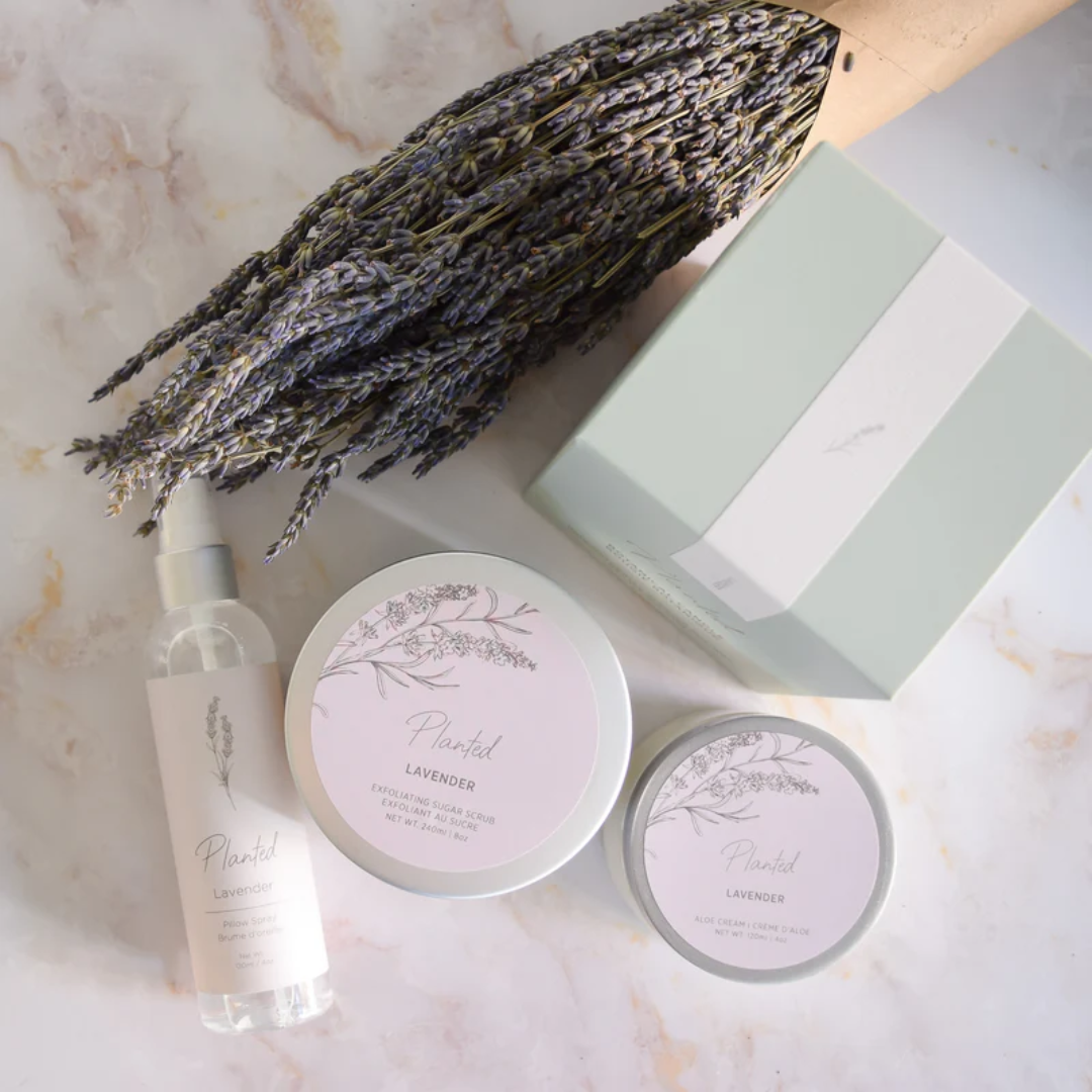 A lavender bouquet, green box, jars and a bottle on a marble counter.