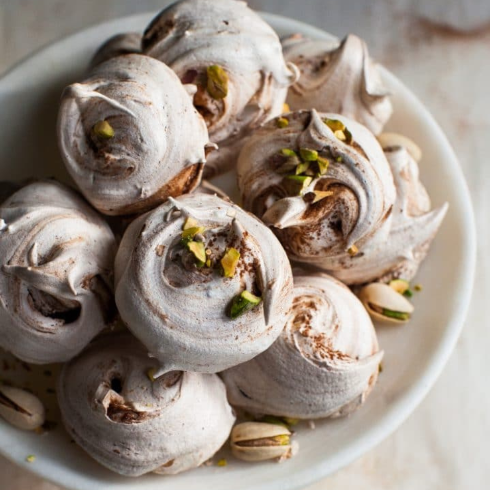 A bowl of meringue cookies with pine tree needles visible overhead