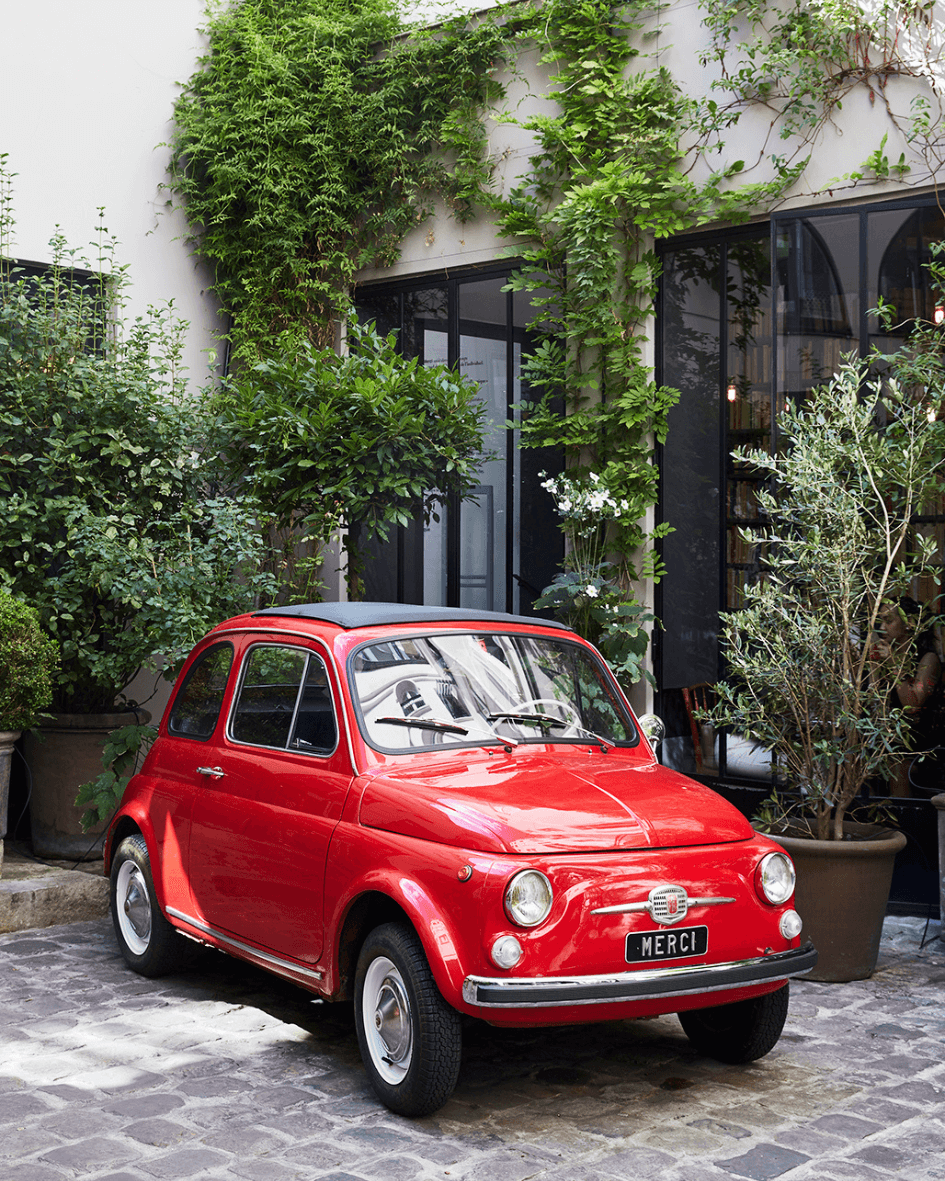 red car in front of doorway and greenery