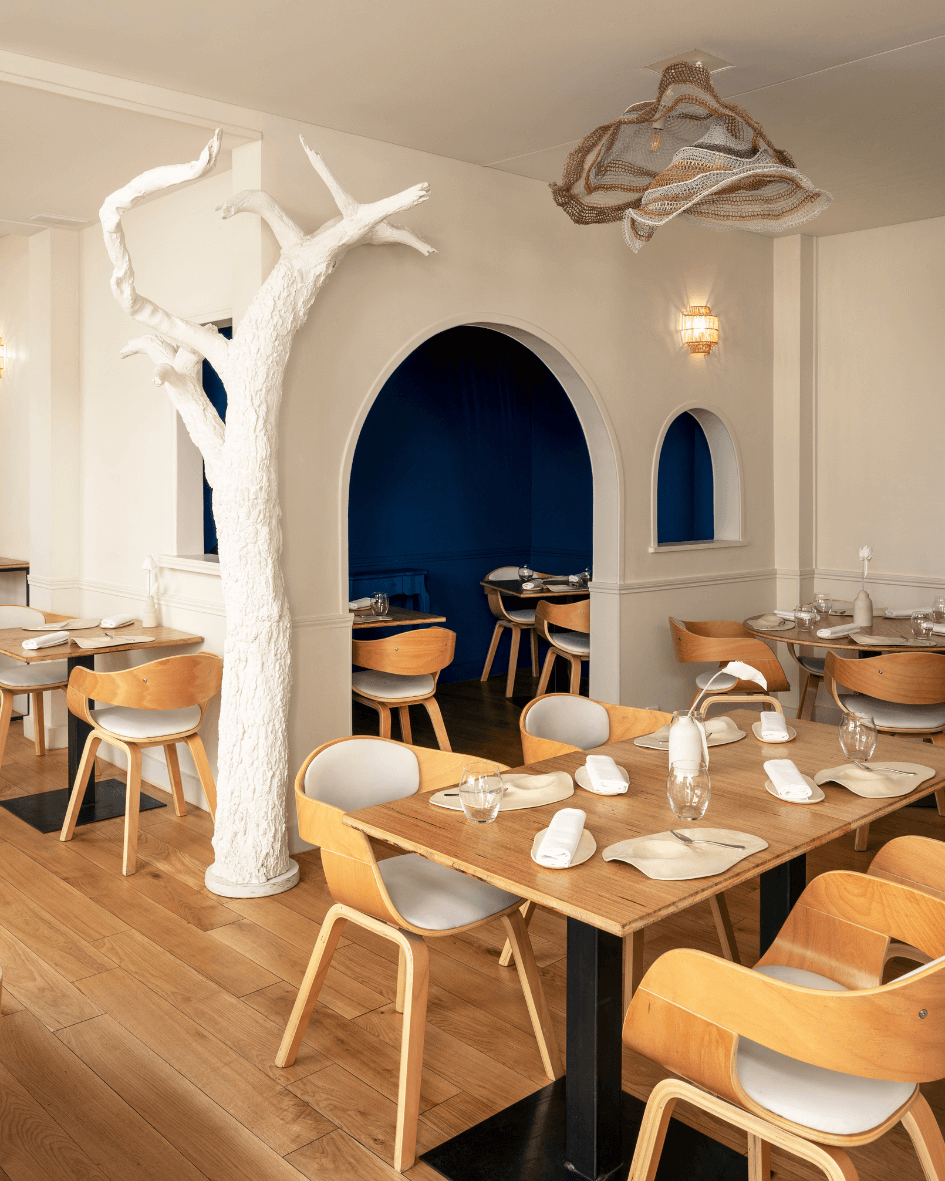 White restaurant interior with light wooden chairs and tables