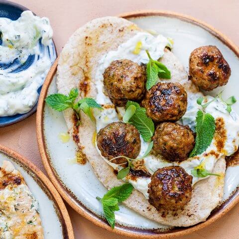 A dish with pita, tzatziki and lamb meatballs.