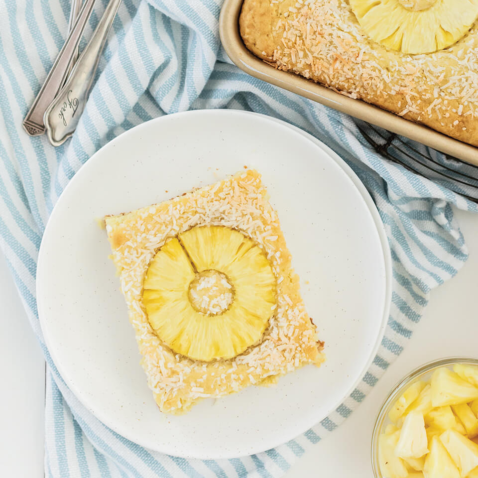 A white plate with a square pancake topped with a pineapple ring