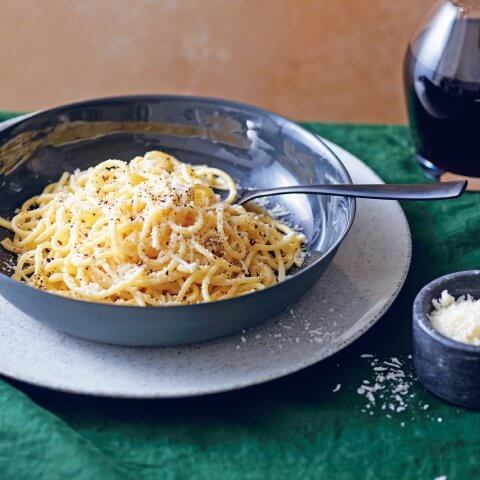 A blue dish with cacio e pepe on a plate.