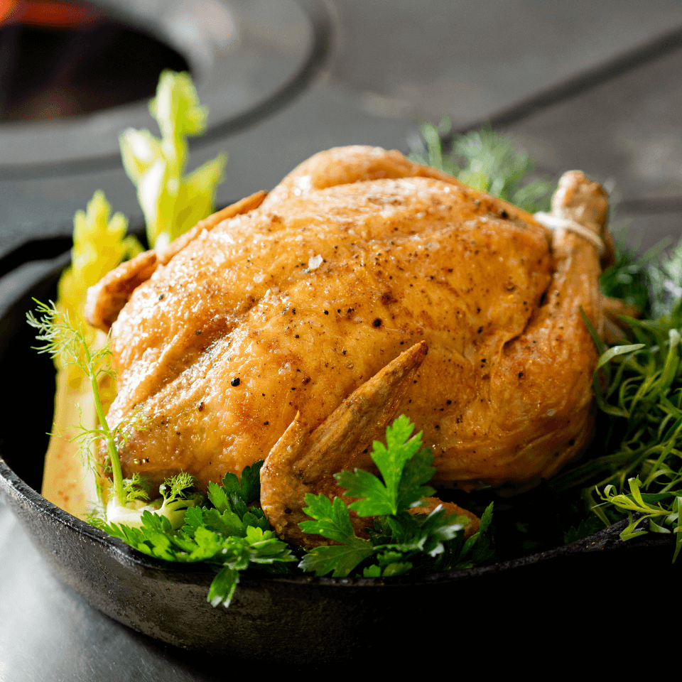 Golden roast turkey in a skillet with fresh herbs and greens.