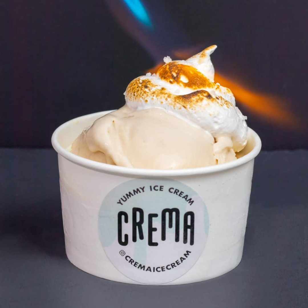 White ice cream scoop topped with white marshmallow fluff being torched.