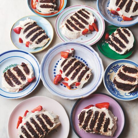 Slices of Ottolenghi's chocolate ripple cake with strawberries on colourful plates.