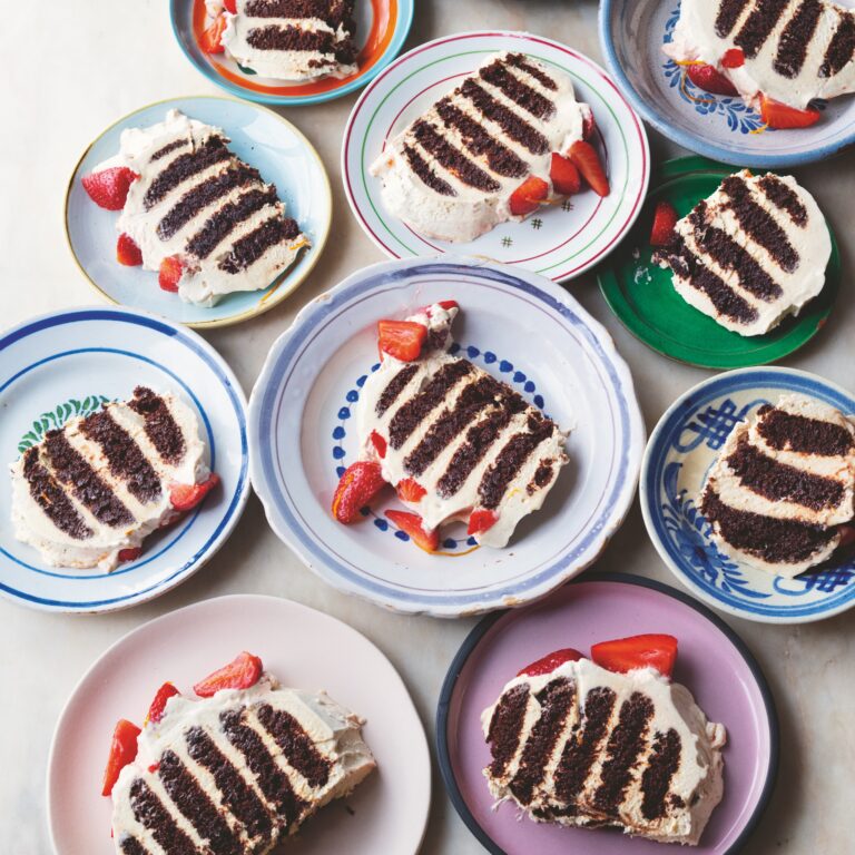 Slices of Ottolenghi's chocolate ripple cake with strawberries on colourful plates.