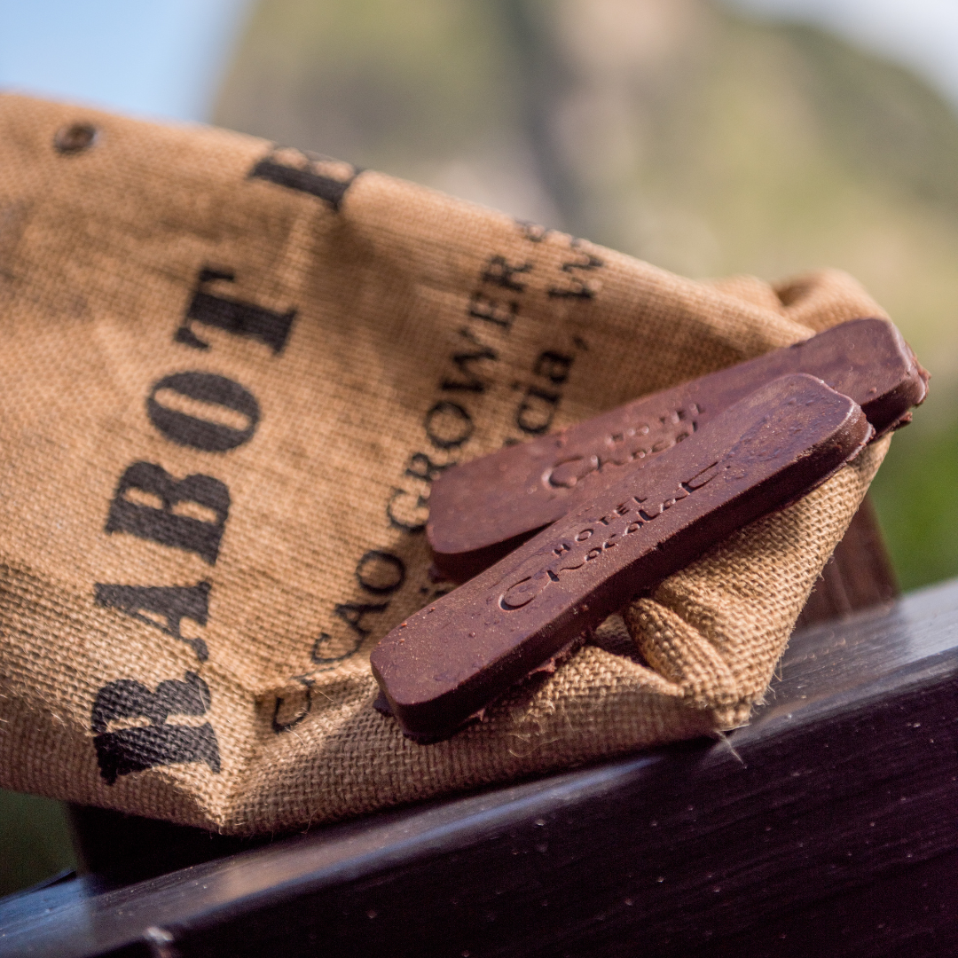 Two thin pieces of chocolate stamped with the words Hotel Chocolat, atop a brown burlap bag. 