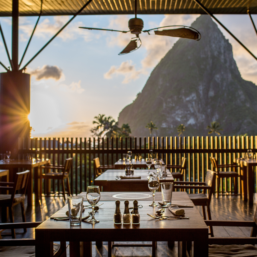 An outdoor dining space with a view of a jagged volcanic mountain. 