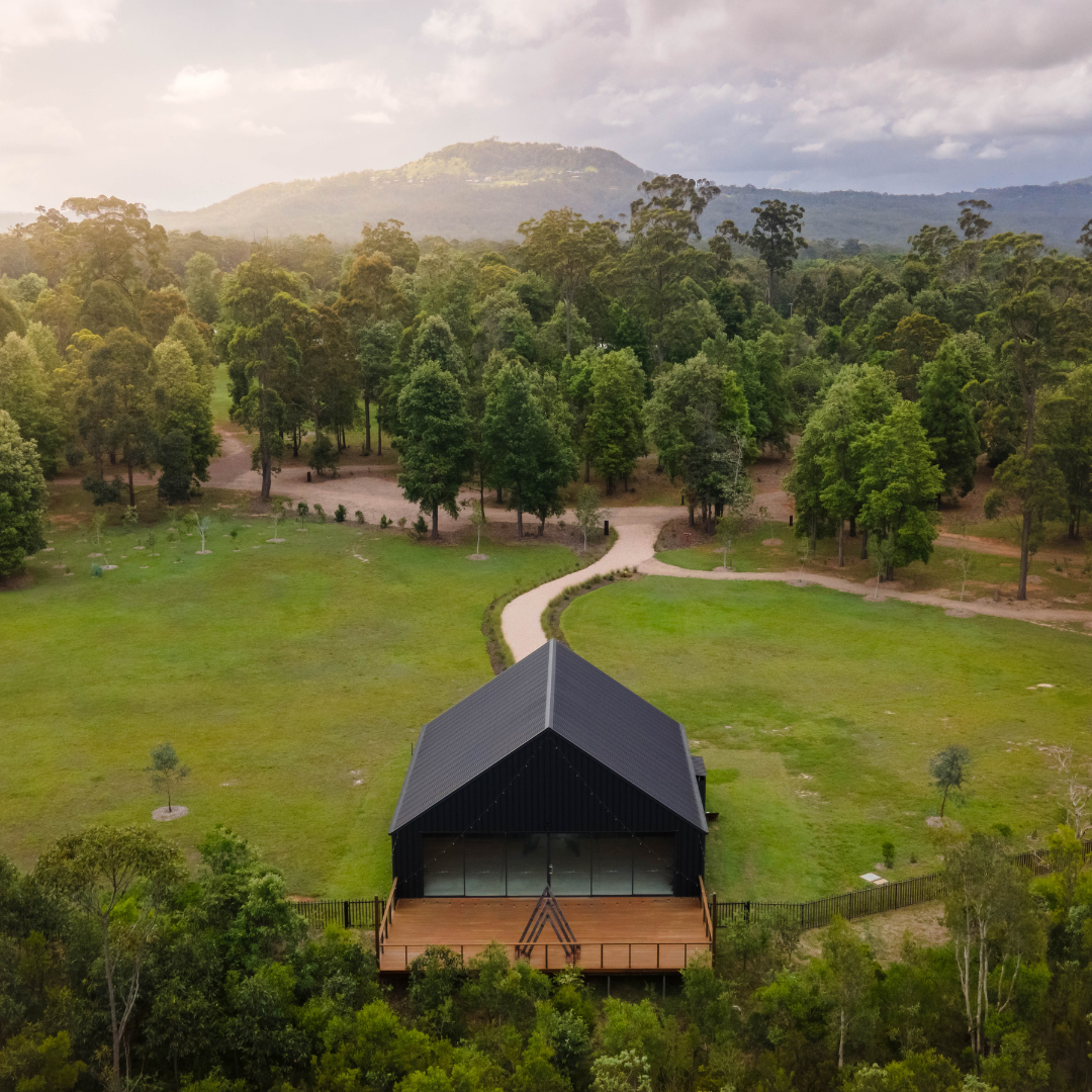 Aerial view of a small lodge surrounded by trees and a mountain view in the distance.
