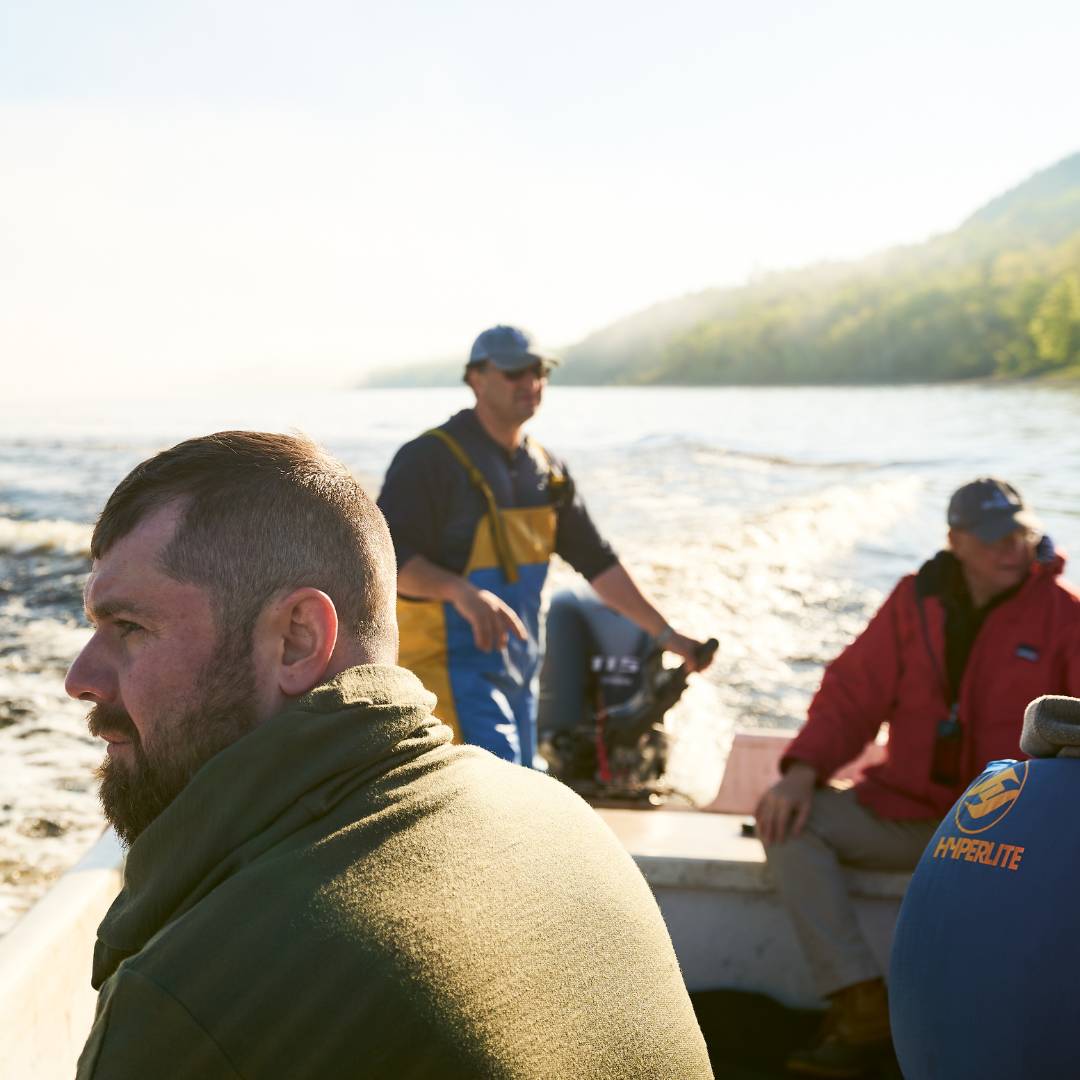 Three men on a boat on the water.